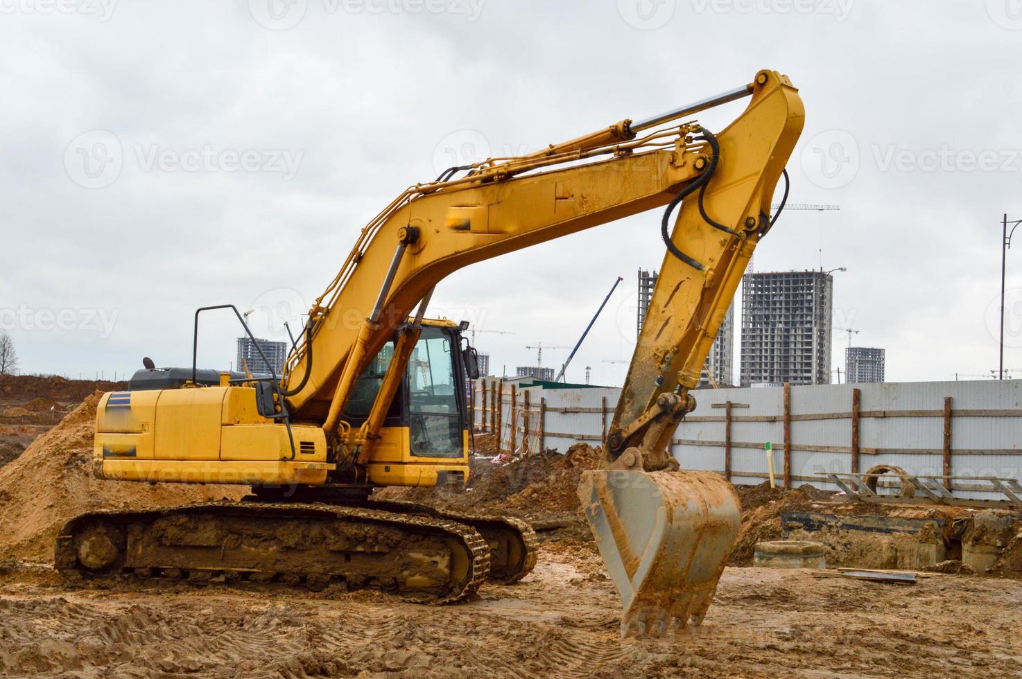 Big bright yellow powerful industrial heavy excavator tractor, bulldozer, specialized construction equipment for road repair during the construction of a new micro-district in a big city photo