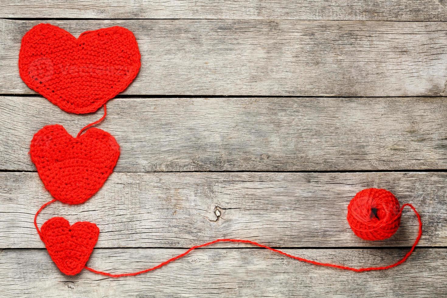 Three red knitted hearts on a gray wooden background, symbolizing love and family. Family relationship, bonds. photo