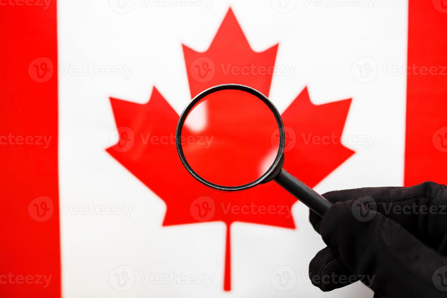 bandera canadiense mirando a través de una lupa. un estudio de la historia y la cultura de la gente de Canadá. el concepto de estudiar geografía, costumbres foto