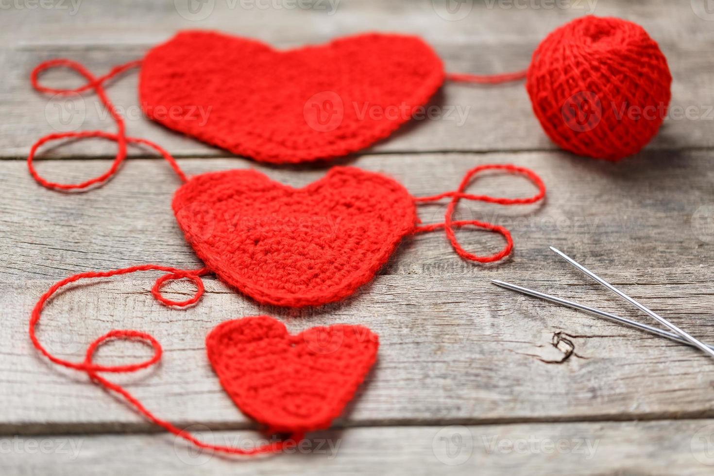 Three red knitted hearts on a gray wooden background, symbolizing love and family. Family relationship, bonds. photo