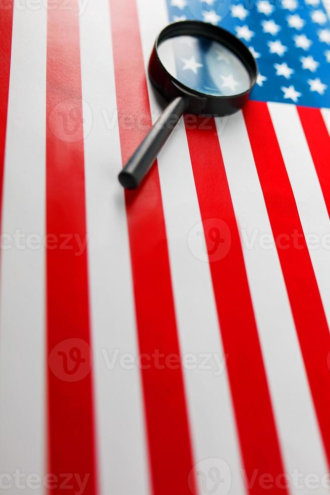 la bandera estadounidense mira a través de una lupa. vigilancia total de los estados unidos. el concepto de amenazas ocultas y control sobre el país foto