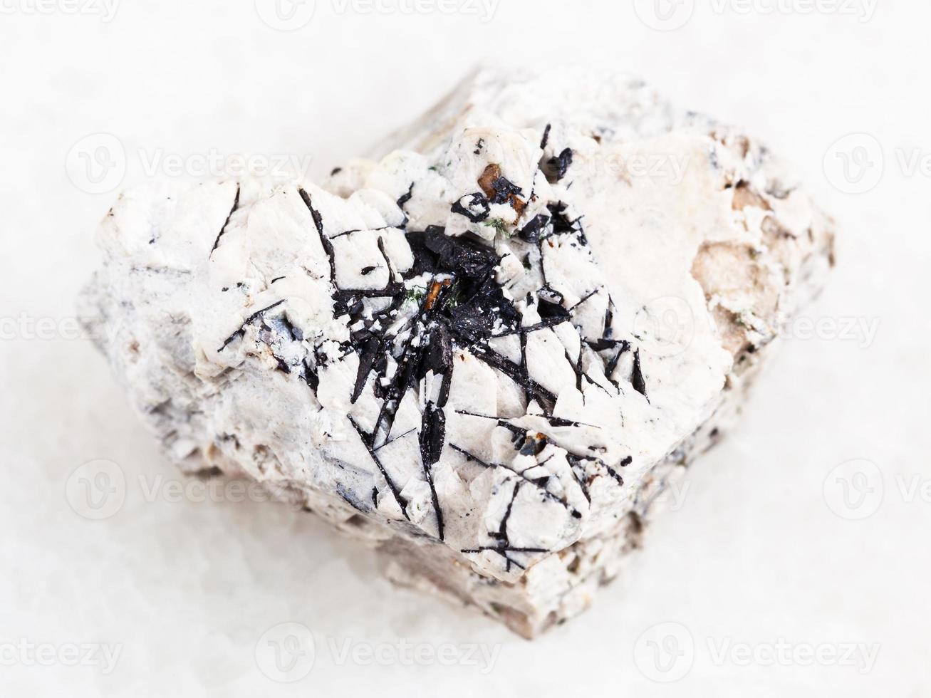 Ilmenite black crystals on raw stone on white photo
