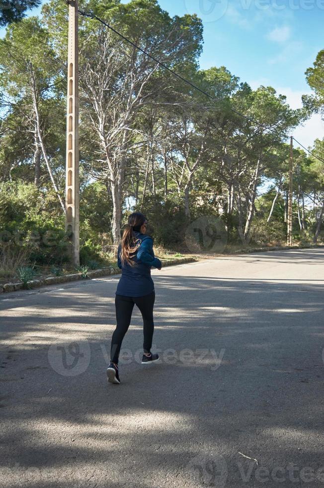 Latin woman, middle-aged, wearing sportswear, training, doing physical exercises, plank, sit-ups, climber's step, burning calories, keeping fit, outdoors by the sea, wearing headphones, smart watch photo