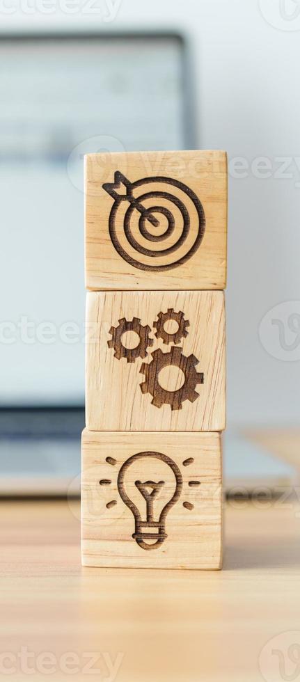 dartboard above Gear and Lightbulb icon block against laptop with business data graph on table. business planning process, goal, strategy, target, mission, action, objective, teamwork and idea concept photo