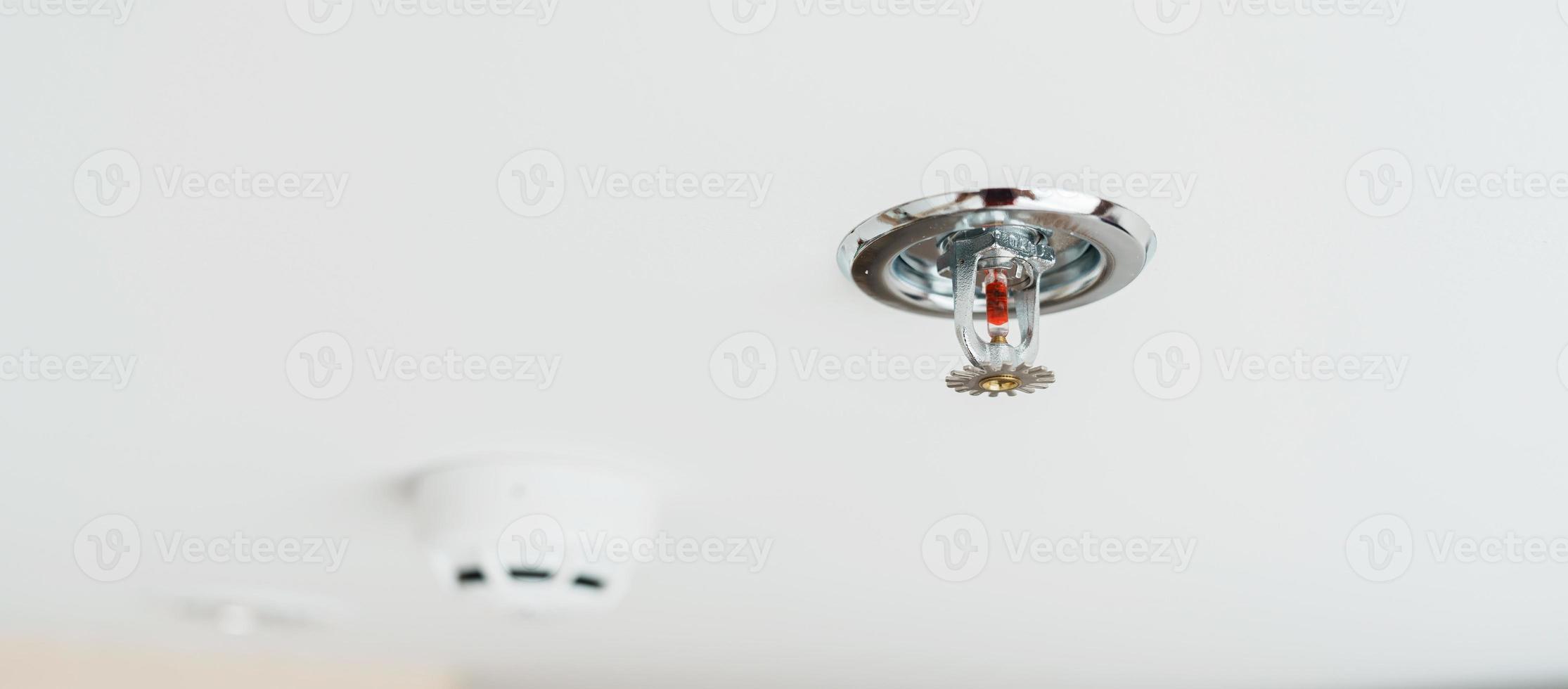 Fire Sprinkler and Smoke sensor detector mounted on roof in home or apartment. Safety and conflagration security concept photo