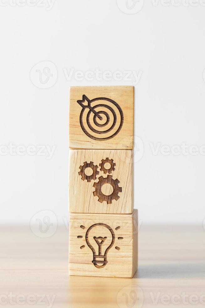 dartboard above Gear and Lightbulb icon block on desk. business planning process, goal, strategy, target, mission, action, objective, teamwork and idea concept photo