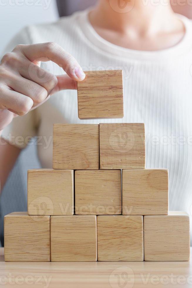 Woman hand placing wood block on the building. Leadership, Business process planning, Risk Management and strategy Concepts photo