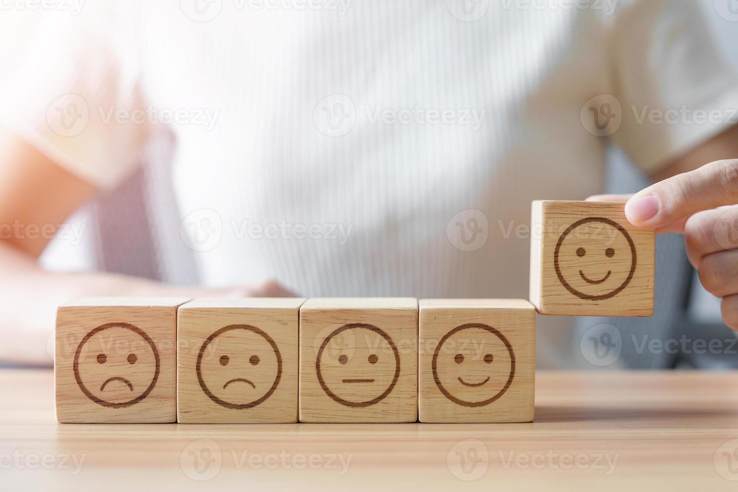 mano eligiendo la cara de la sonrisa del bloque de emociones. revisión del cliente, buena experiencia, comentarios positivos, satisfacción, encuesta, servicio de calificación, evaluación, estado de ánimo, concepto del día mundial de la salud mental foto