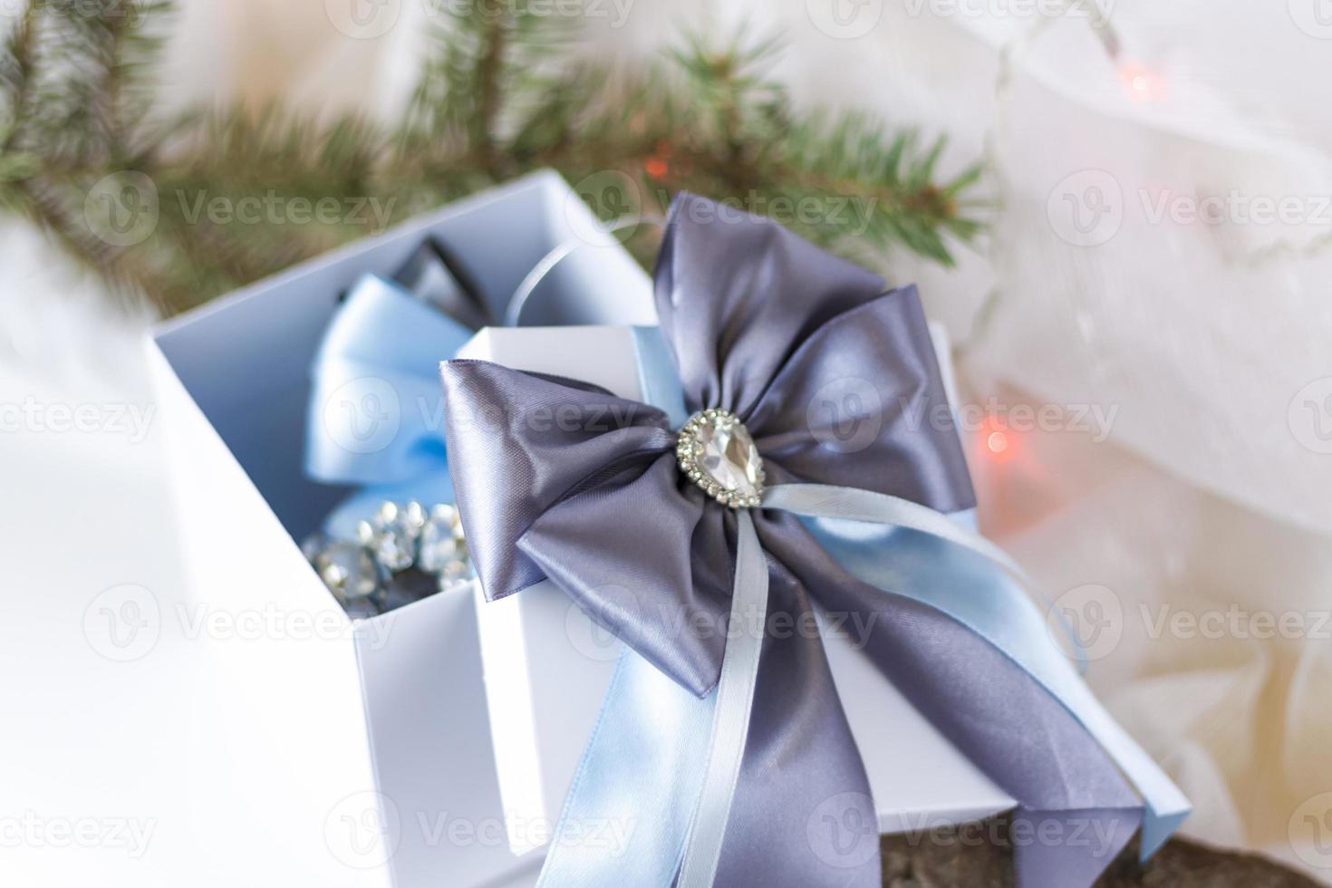 A Christmas gift decorated with a beautiful bow on a light background with a fir twig. Gifts, joy, surprise. Selective focus. the concept of Christmas and New Year. photo