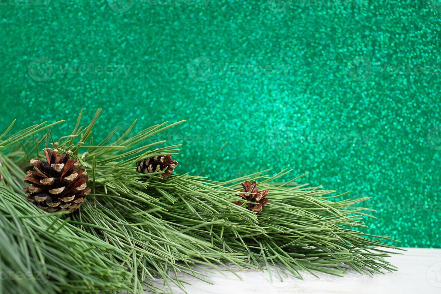 Natural pine tree Branches with cones on white table. Blurred green bokeh. Christmas, New Year. Copy space photo