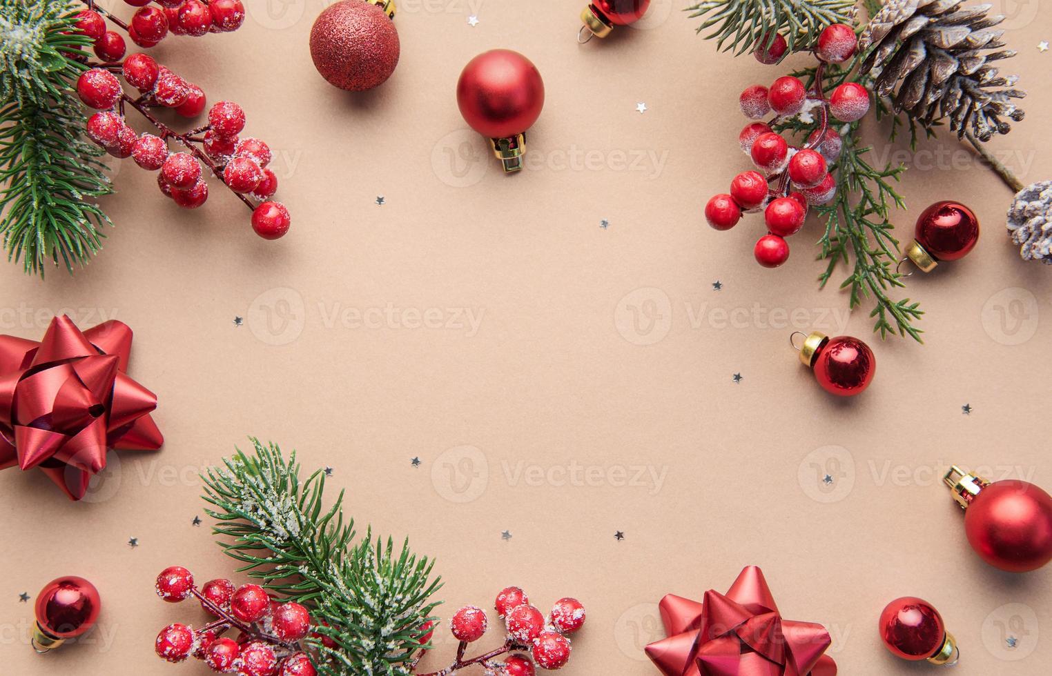 brillante marco navideño de abeto, adornos navideños rojos sobre fondo beige. foto