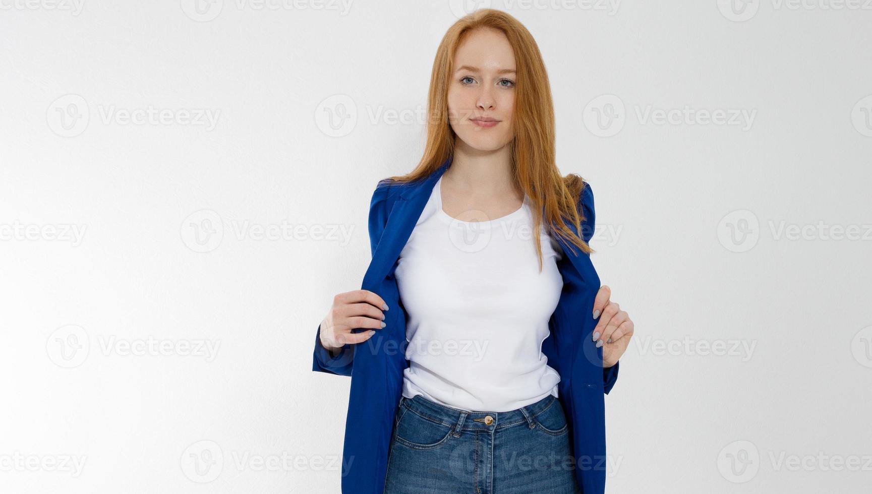 Happy red haired business woman in template blank white t shirt and stylish jacket isolated on gray background. Self career and job consulting knowledge. Young ceo entrepreneur and casual clothes photo