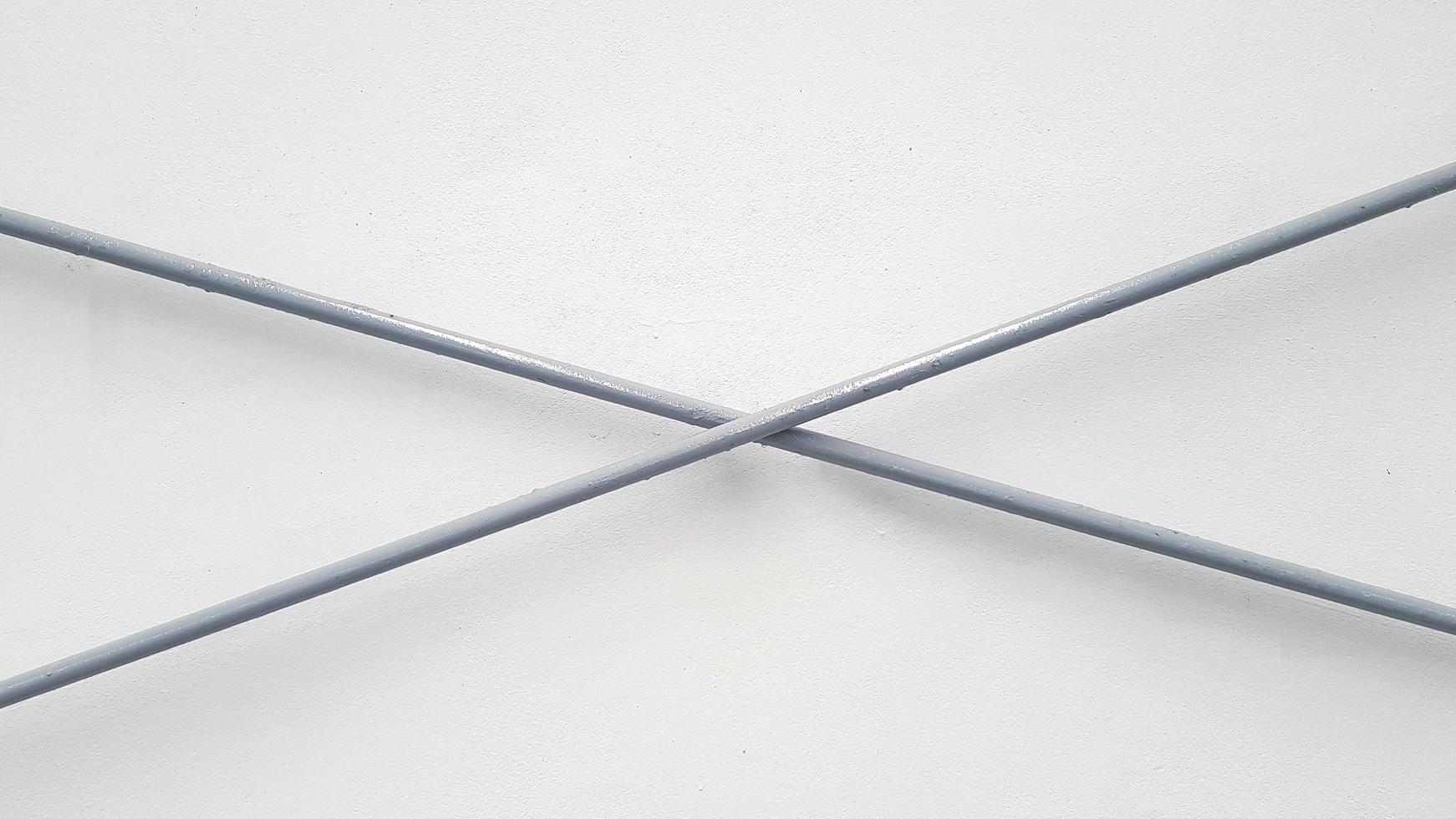 Gray or grey stainless steel wire cross on white wall background. Iron line and Shape geometric concept photo