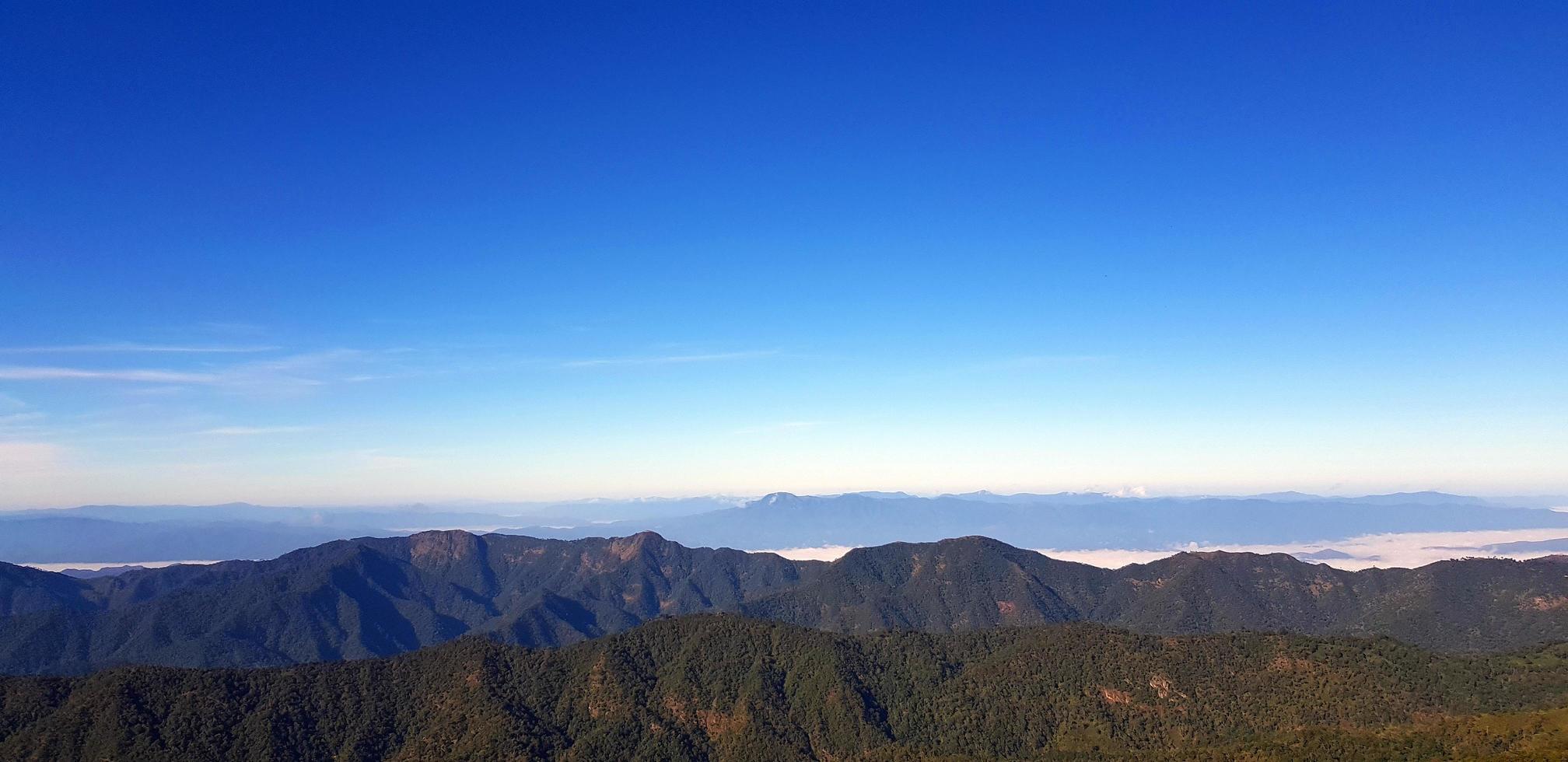 Landscape view of green mountain hill with mist and clear blue sky background with copy space on above at Doi Pha Hom Pok National Park, Chiang Mai, Thailand. Natural wallpaper and Beauty of nature. photo