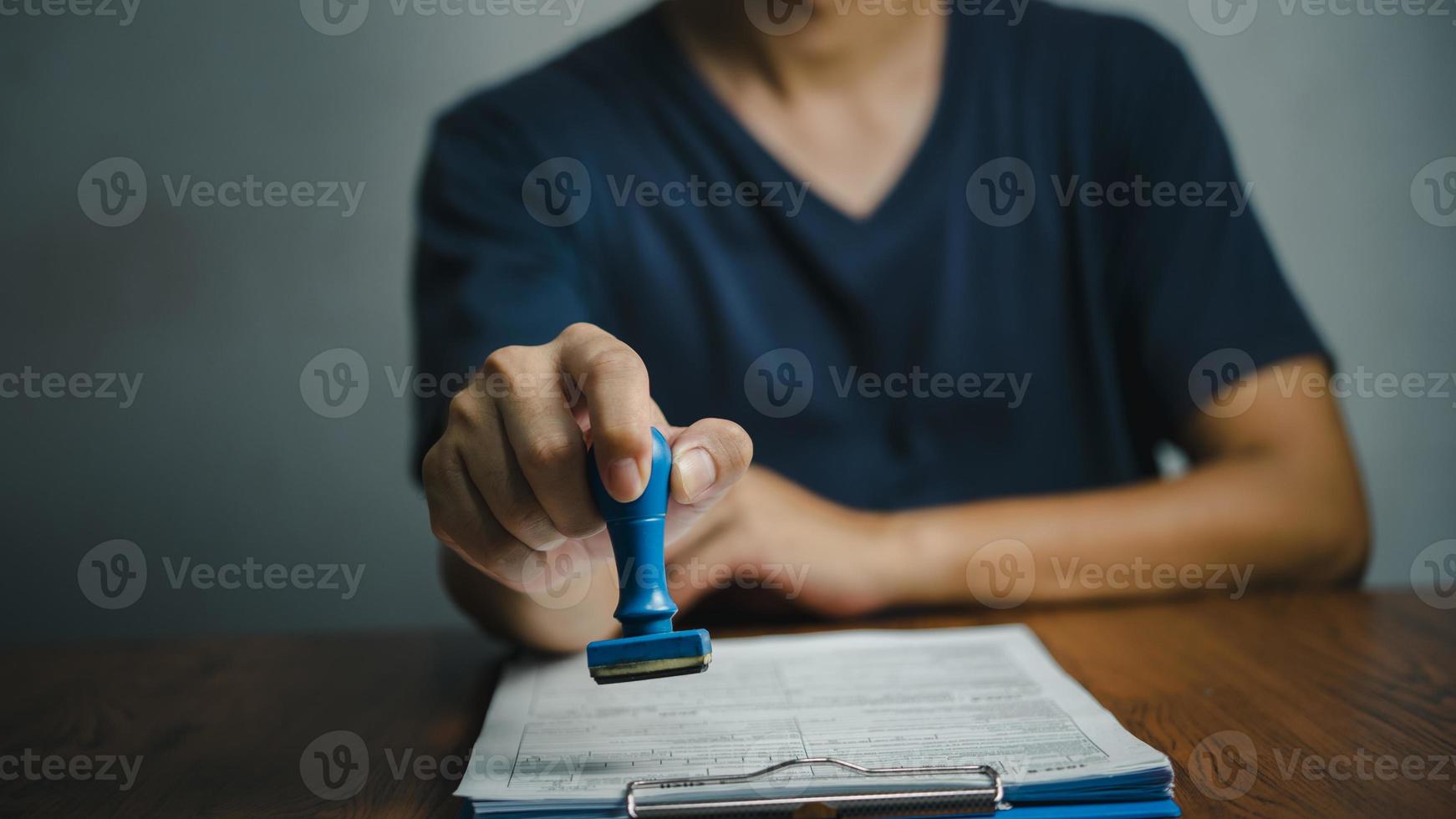 hombre que sella la aprobación de la banca de financiación del trabajo o los documentos de marketing de inversión en el escritorio. foto