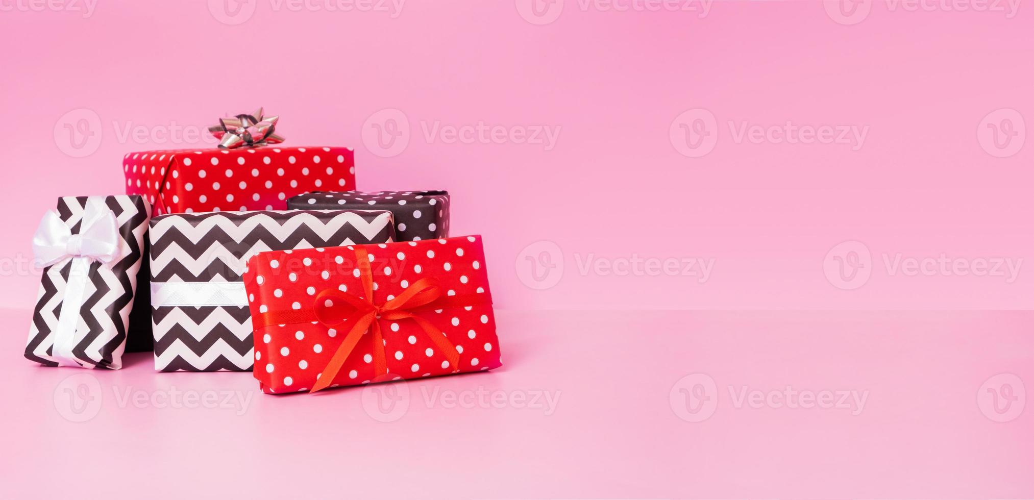 feliz navidad, año nuevo y concepto de evento de venta. cajas de regalo con lazo de cinta sobre fondo rosa foto