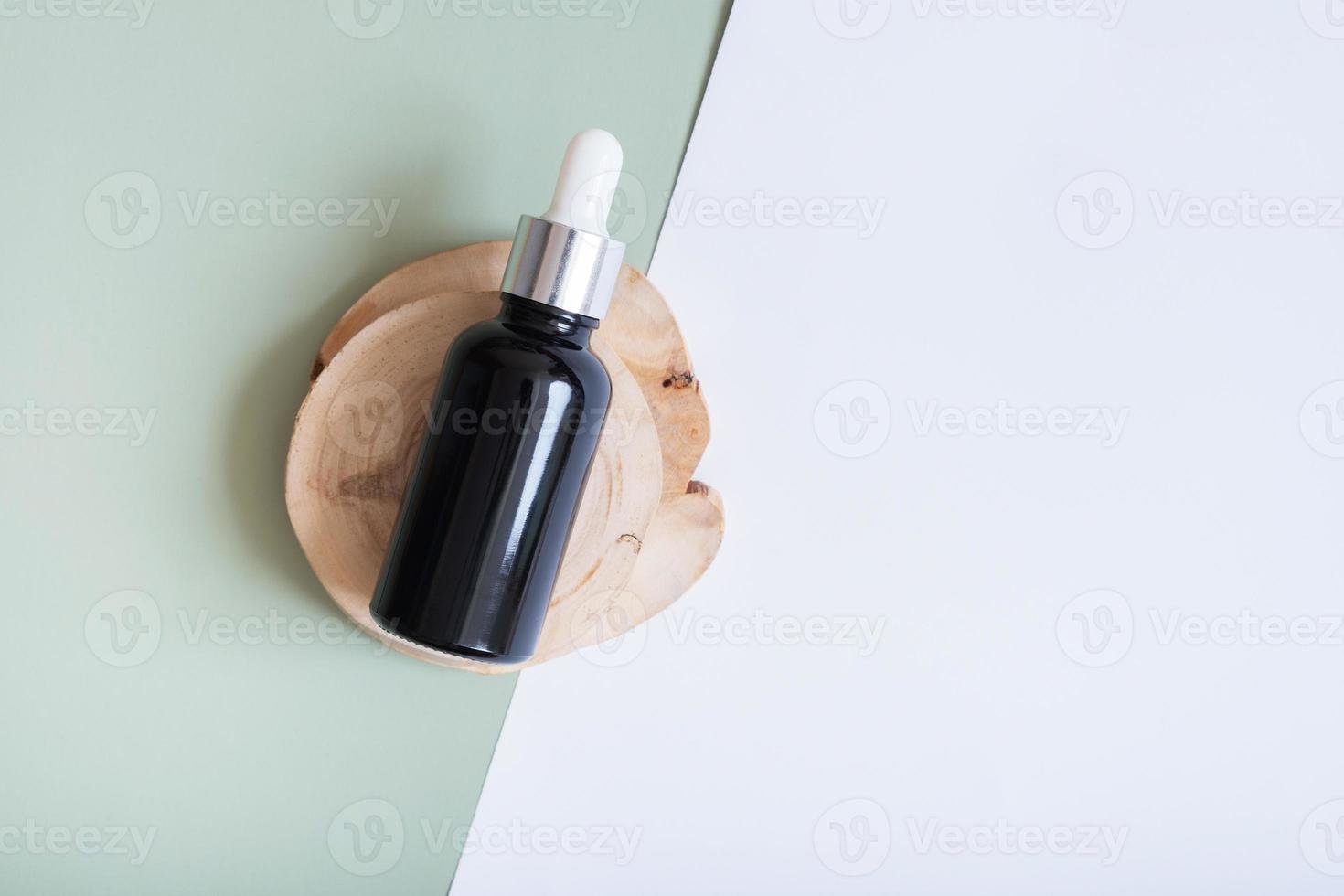 Cosmetic bottle with pipette on wooden slice top view, flat lay on colored background. Natural cosmetic concept photo