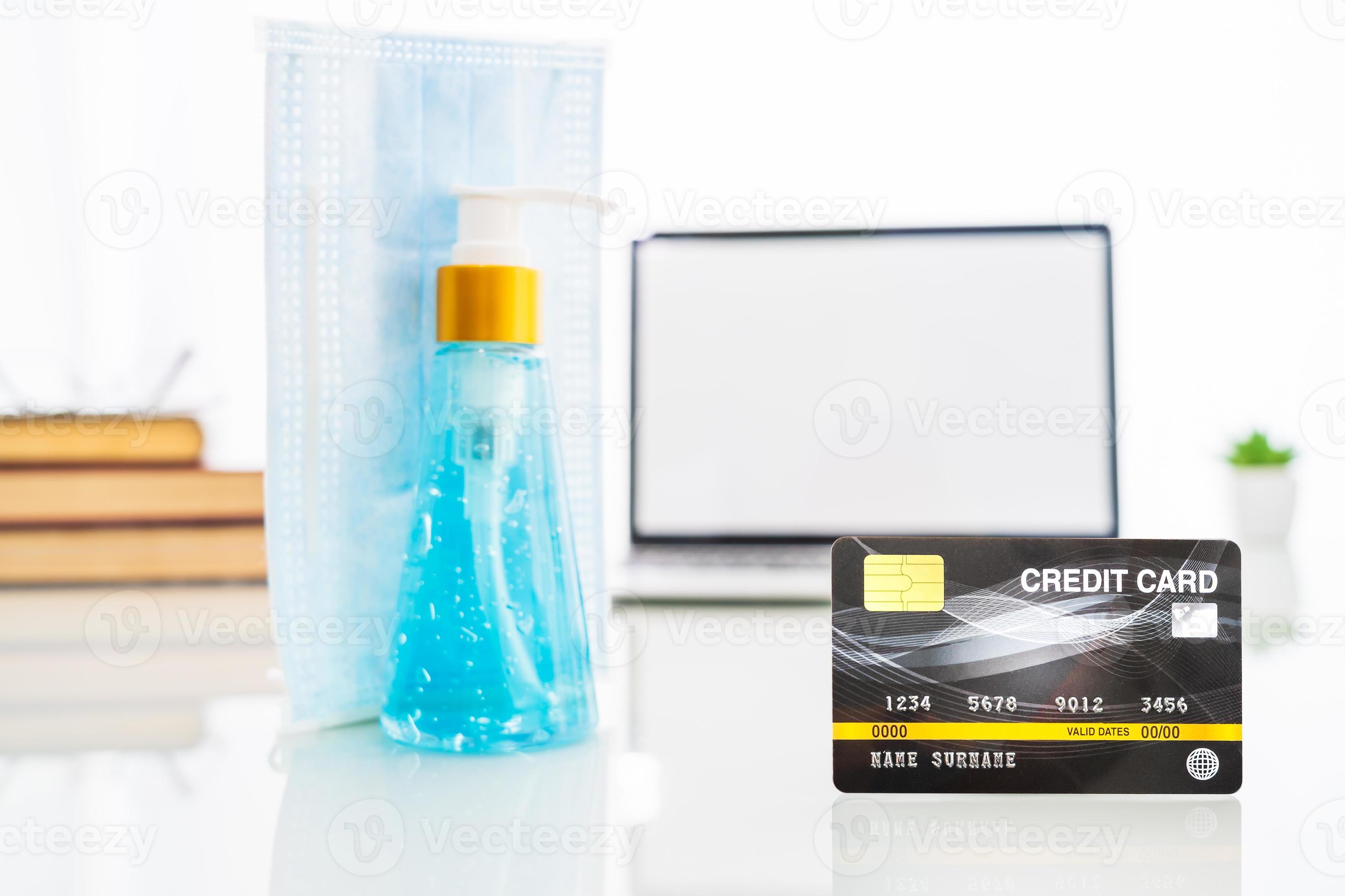 Credit card front of laptop screen with hand sanitizer and surgical