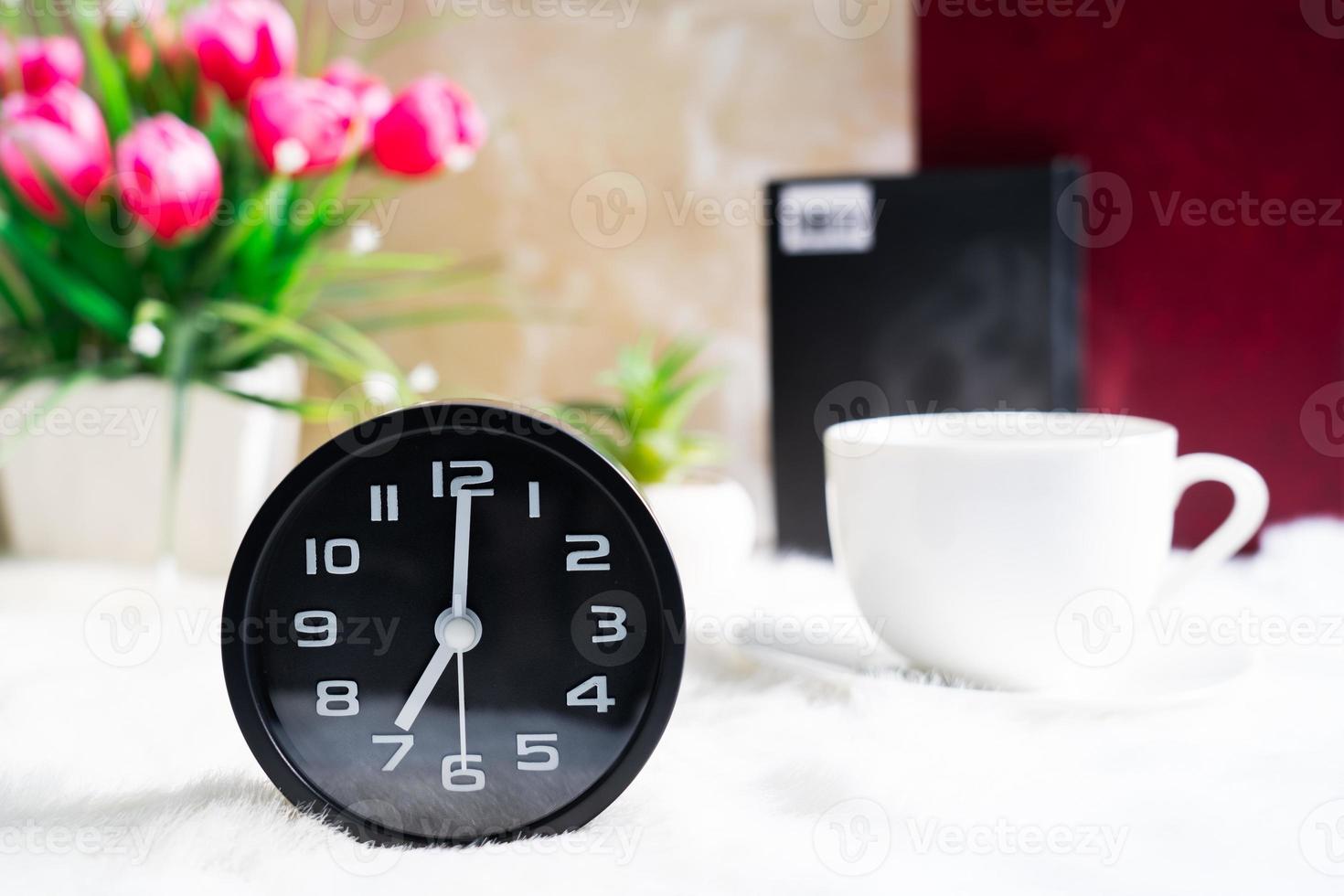 Black clock and cup of coffee photo