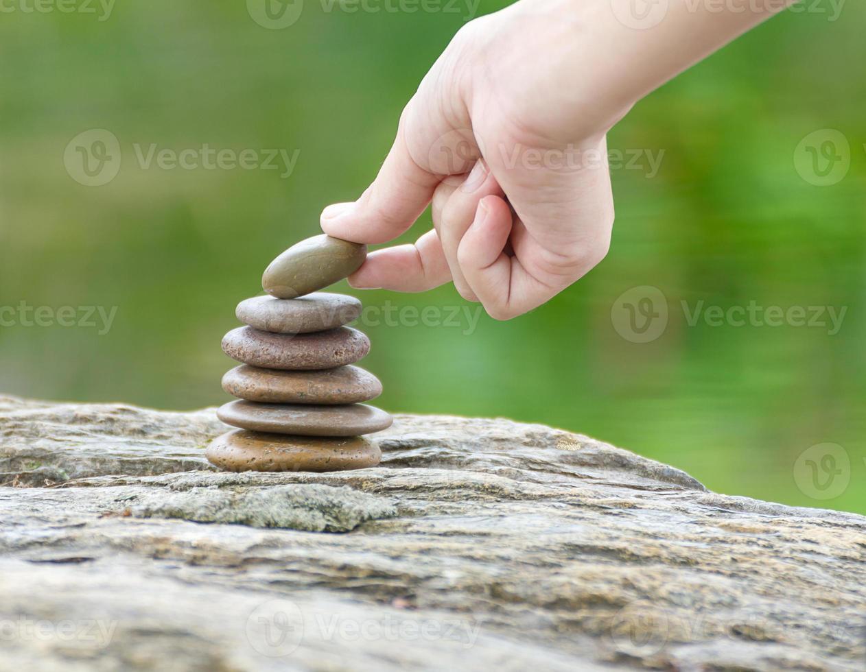 mano poner piedra construyendo un montón de piedras zen foto