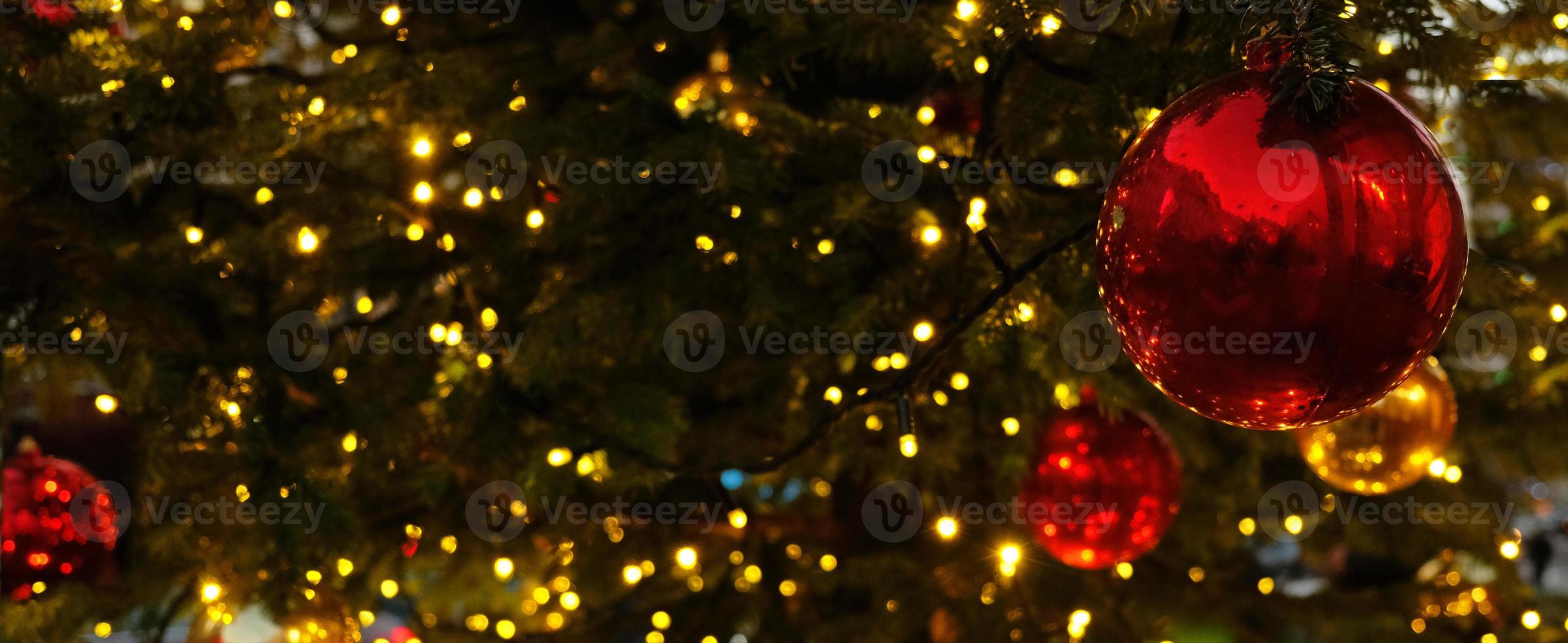 Christmas banner with copy space and sparkles for greeting card. Fir branch with red balls, festive yellow lights and bokeh. Perfect content for advertising banners, gift card or creative projects. photo