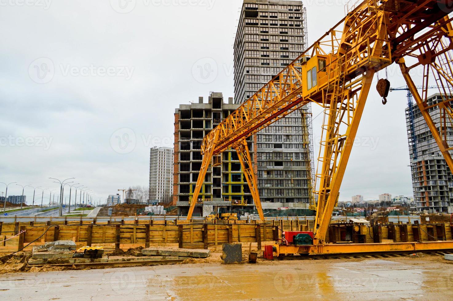 High heavy yellow metal iron load-bearing construction stationary industrial powerful gantry crane of bridge type on supports for lifting cargo on a modern construction site of buildings and houses photo