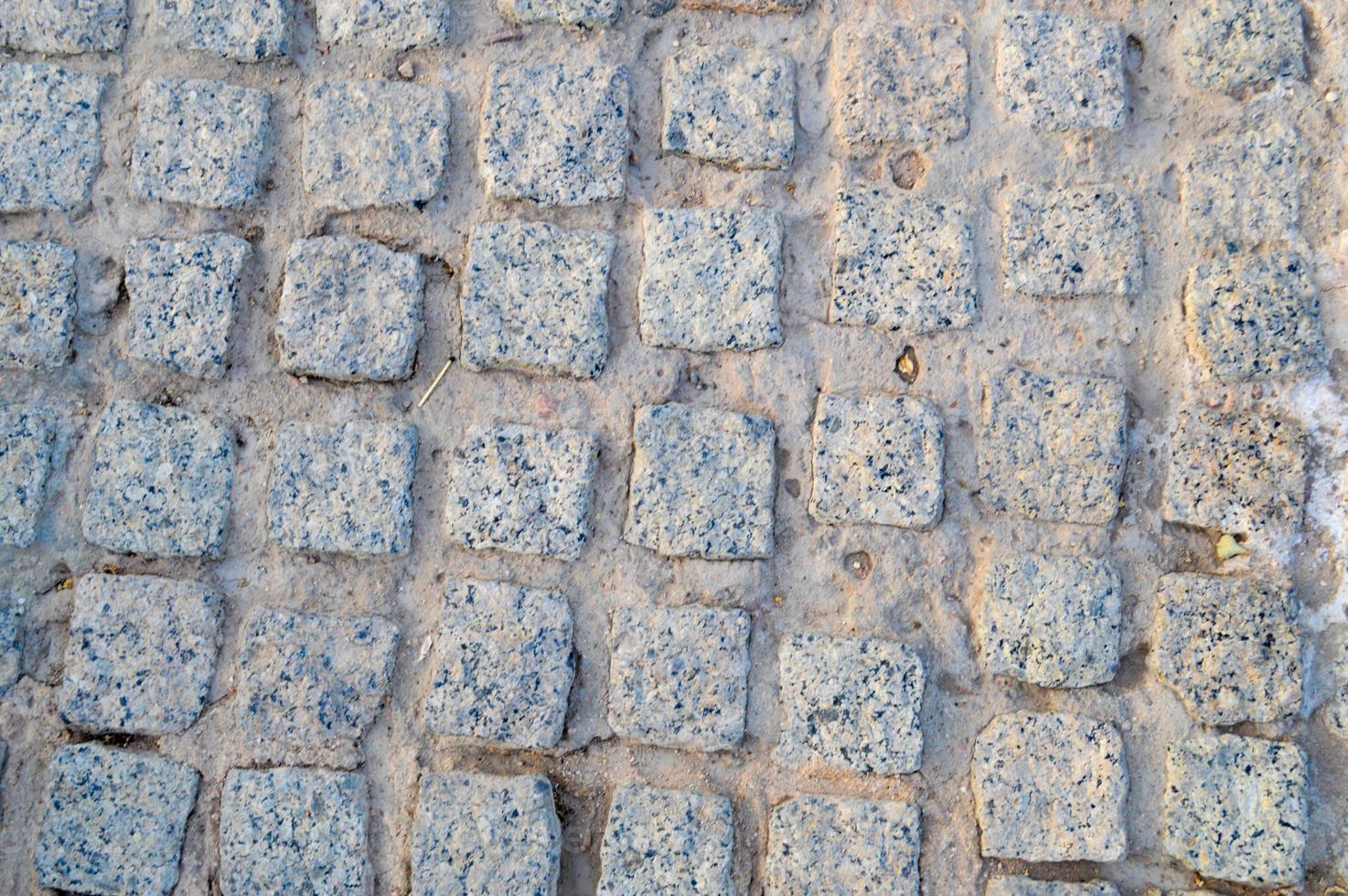 Texture of a stone wall, roads from stones, bricks, cobblestones, tiles with sandy seams of gray ancient natural old yellow with sharp edges. The background photo