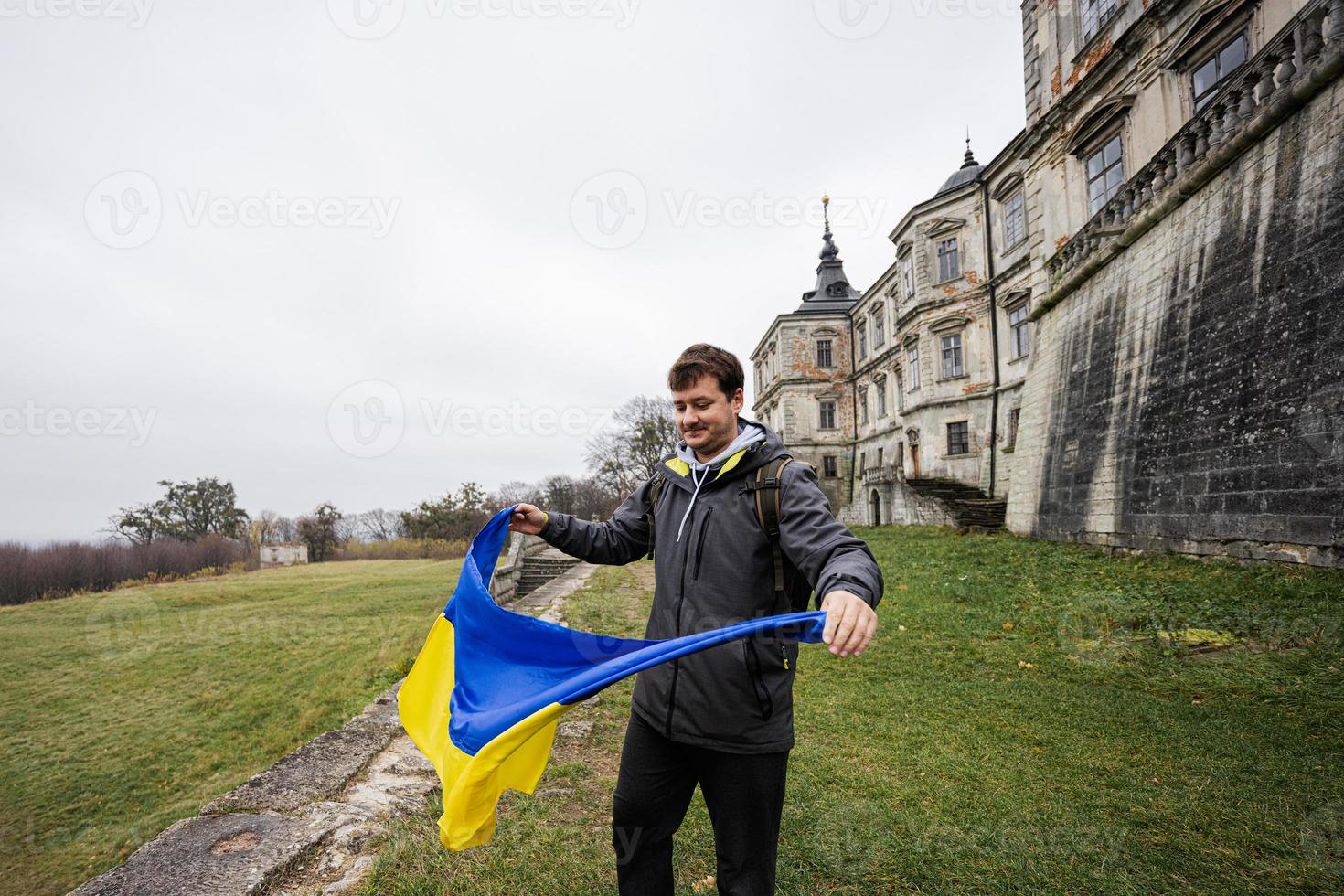 Man tourist with Ukrainian flag at hands visit Pidhirtsi Castle, Lviv region, Ukraine. photo