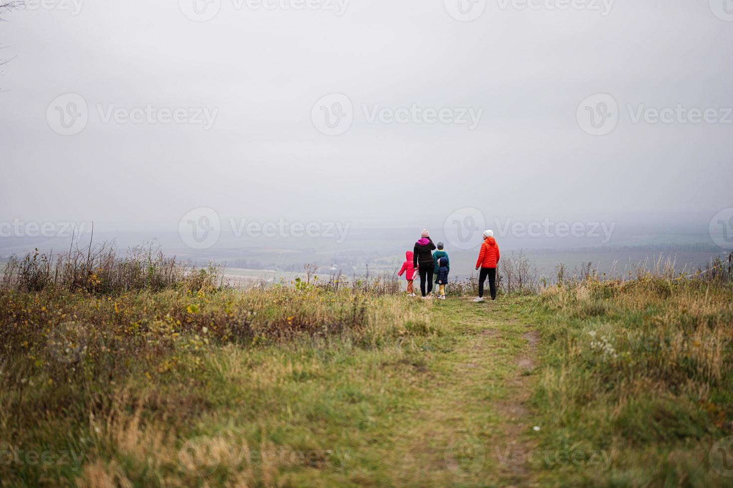 Mother with four kids against hill in foggy weather. photo