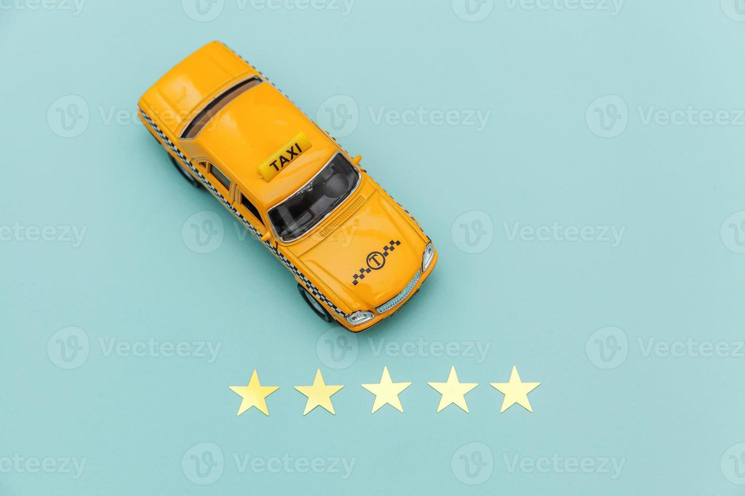 taxi de coche de juguete amarillo y calificación de 5 estrellas aislado sobre fondo azul. aplicación de teléfono inteligente del servicio de taxi para buscar en línea llamadas y reservar el concepto de taxi. símbolo de taxi. copie el espacio foto