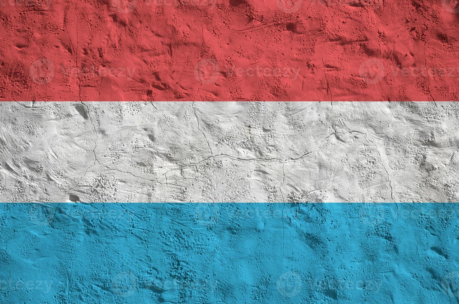 Luxembourg flag depicted in bright paint colors on old relief plastering wall. Textured banner on rough background photo