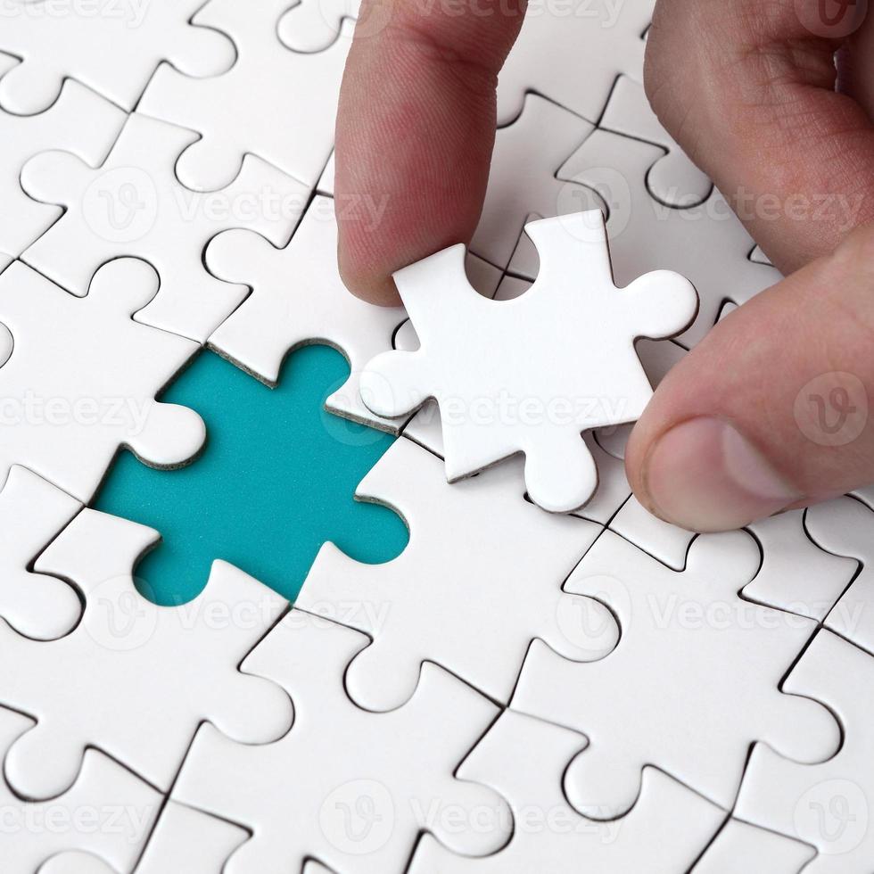 The human hand fills the last missing elements of the surface from the jigsaw puzzle. The concept of the completion of the initiated cases photo