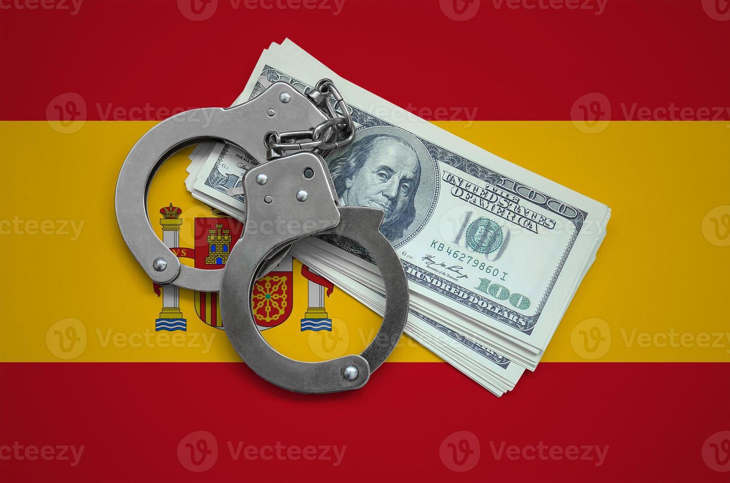 Spain flag  with handcuffs and a bundle of dollars. Currency corruption in the country. Financial crimes photo