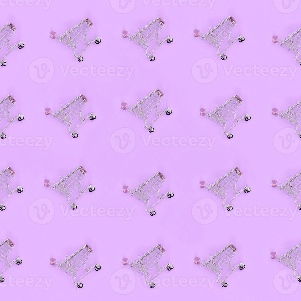 Shopping addiction, shopping lover or shopaholic concept. Many small empty shopping carts perform a pattern on a pastel colored paper background. Flat lay composition, top view photo