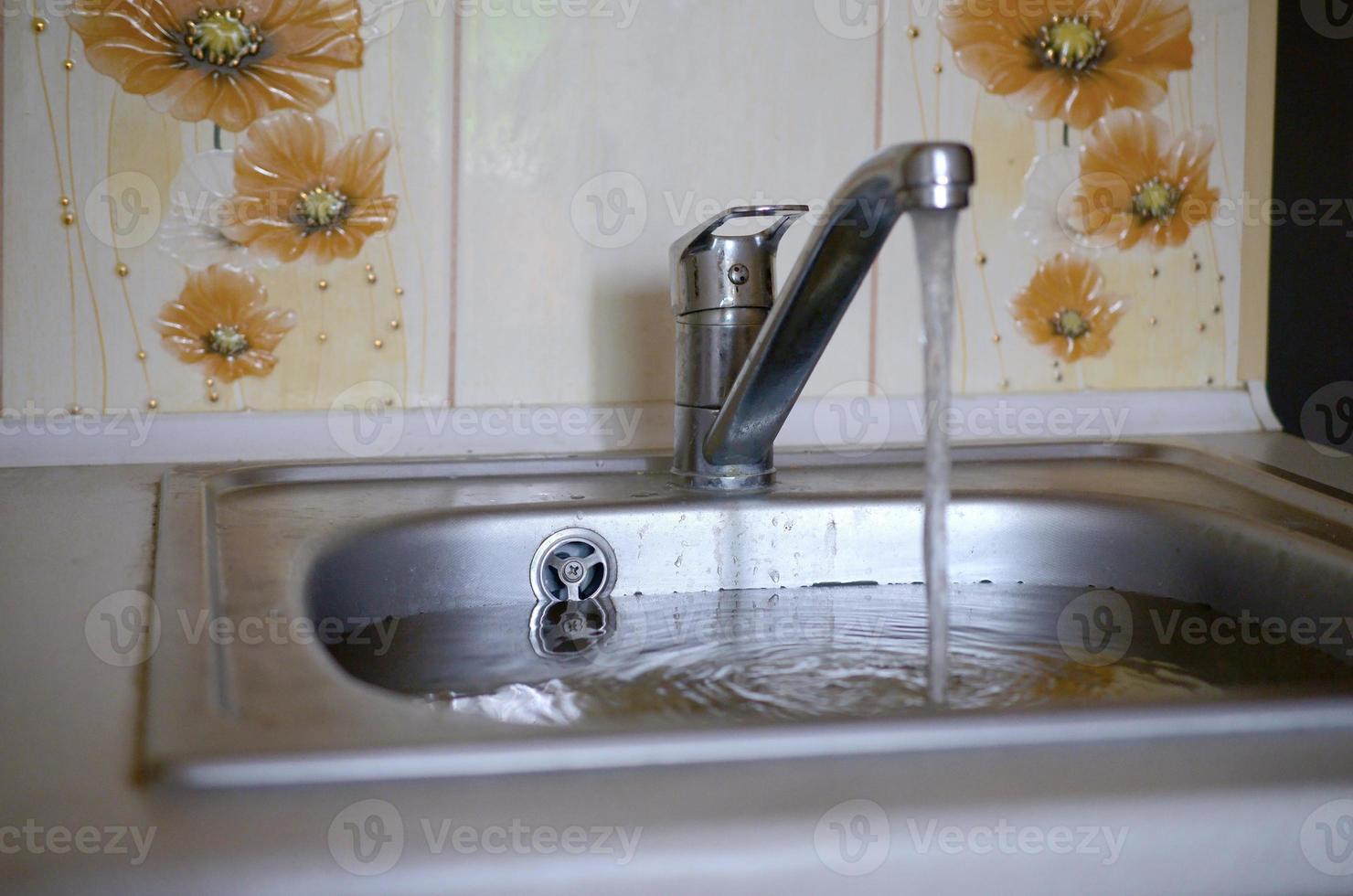 Stainless steel sink plug hole close up full of water and particles of food photo