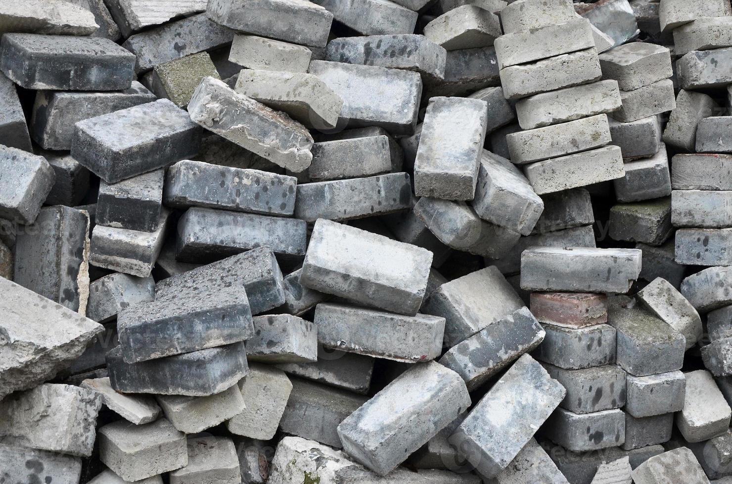 A large pile of disassembled paving slabs. A lot of square stones before the reconstruction of the pavement site photo