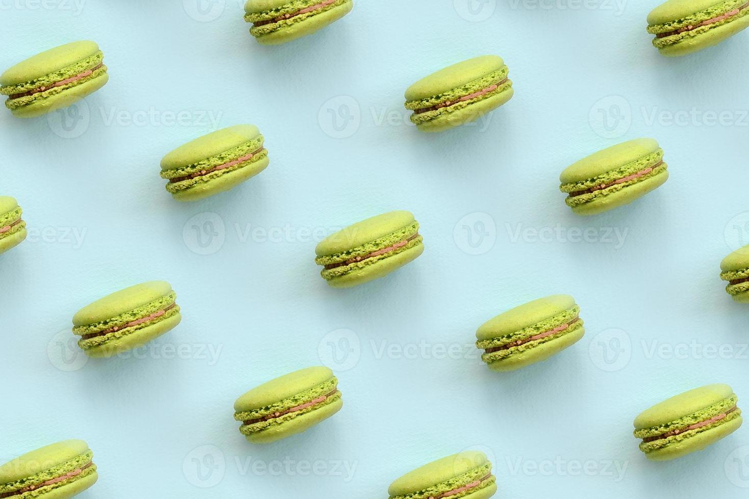 Green dessert cake macaron or macaroon on trendy pastel blue background top view. Flat lay pattern composition photo