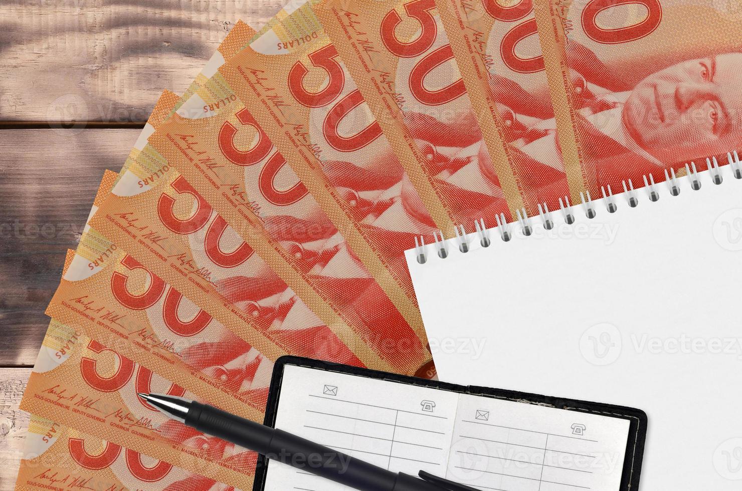 50 Canadian dollars bills fan and notepad with contact book and black pen. Concept of financial planning and business strategy photo