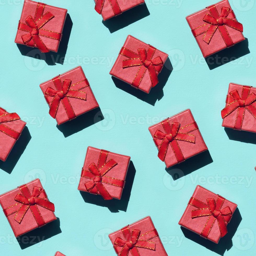 Many small red pink gift boxes on texture background of fashion trendy pastel blue color paper in minimal concept. Abstract pattern photo