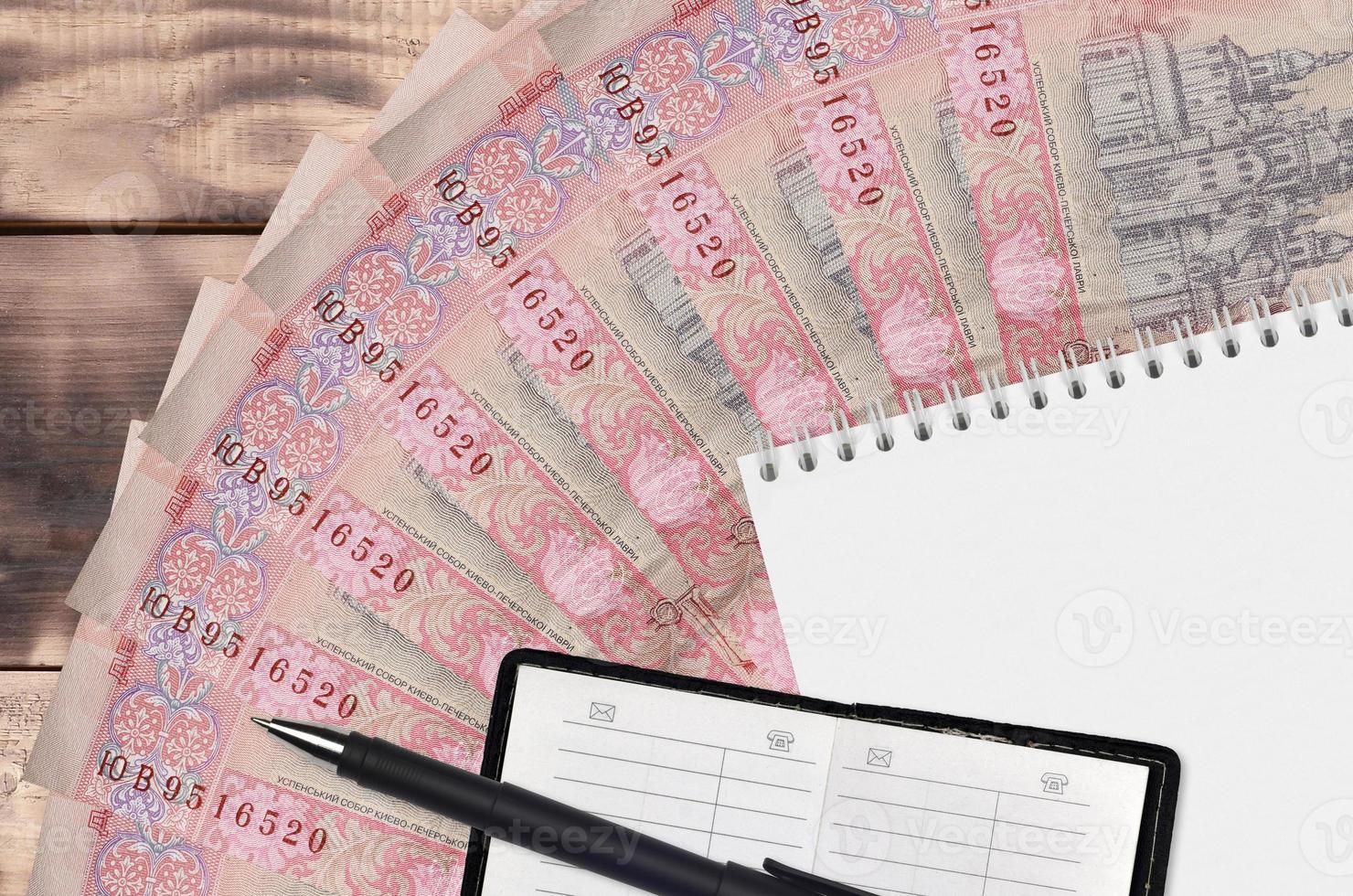 10 Ukrainian hryvnias bills fan and notepad with contact book and black pen. Concept of financial planning and business strategy photo