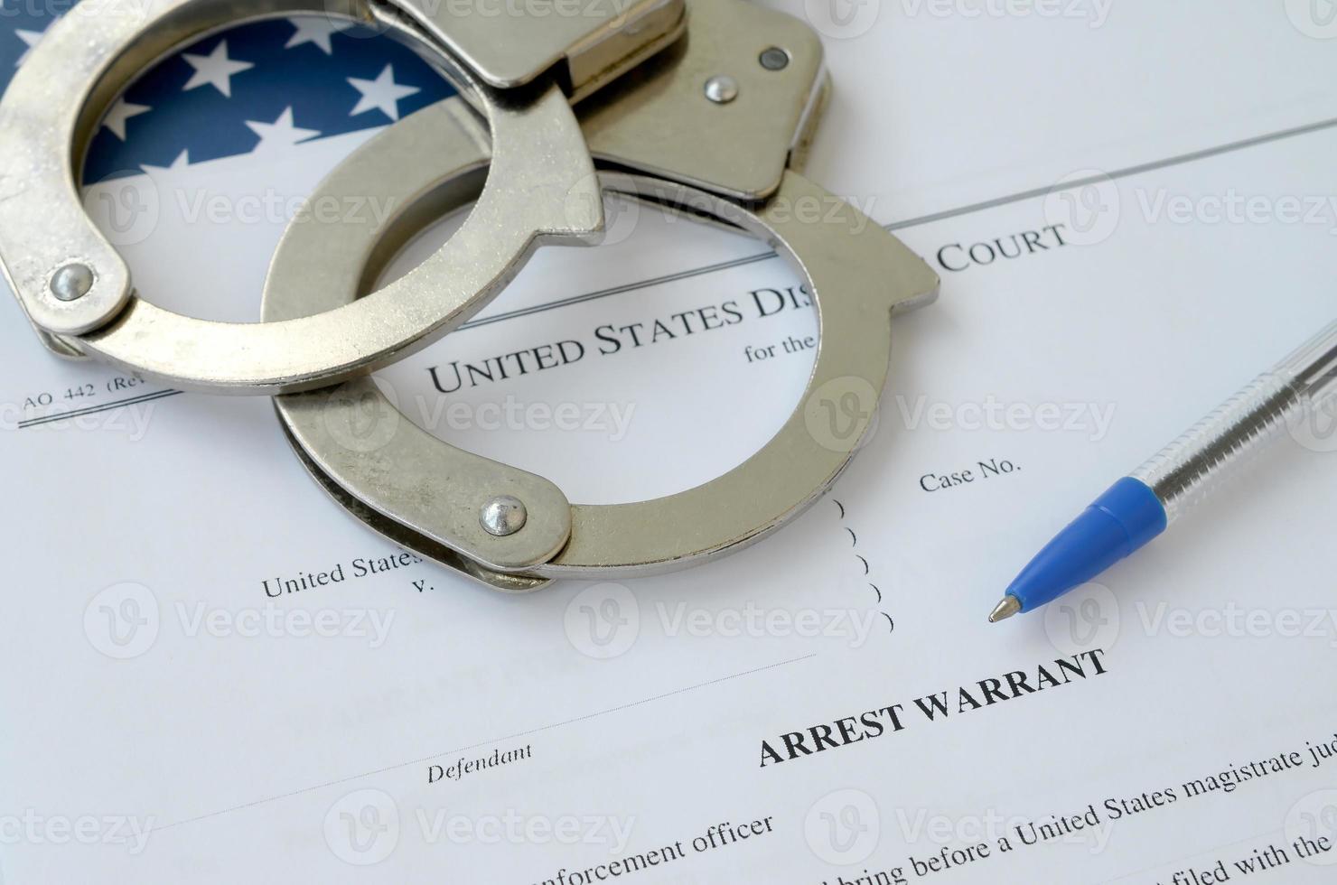 District Court Arrest Warrant court papers with handcuffs and blue pen on United States flag. Concept of permission to arrest suspect photo