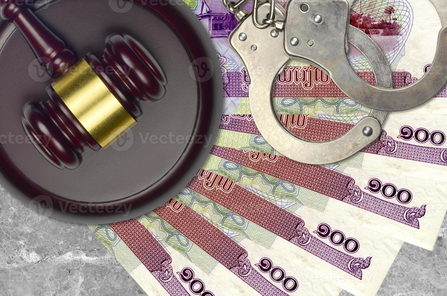 100 Cambodian riels bills and judge hammer with police handcuffs on court desk. Concept of judicial trial or bribery. Tax avoidance photo