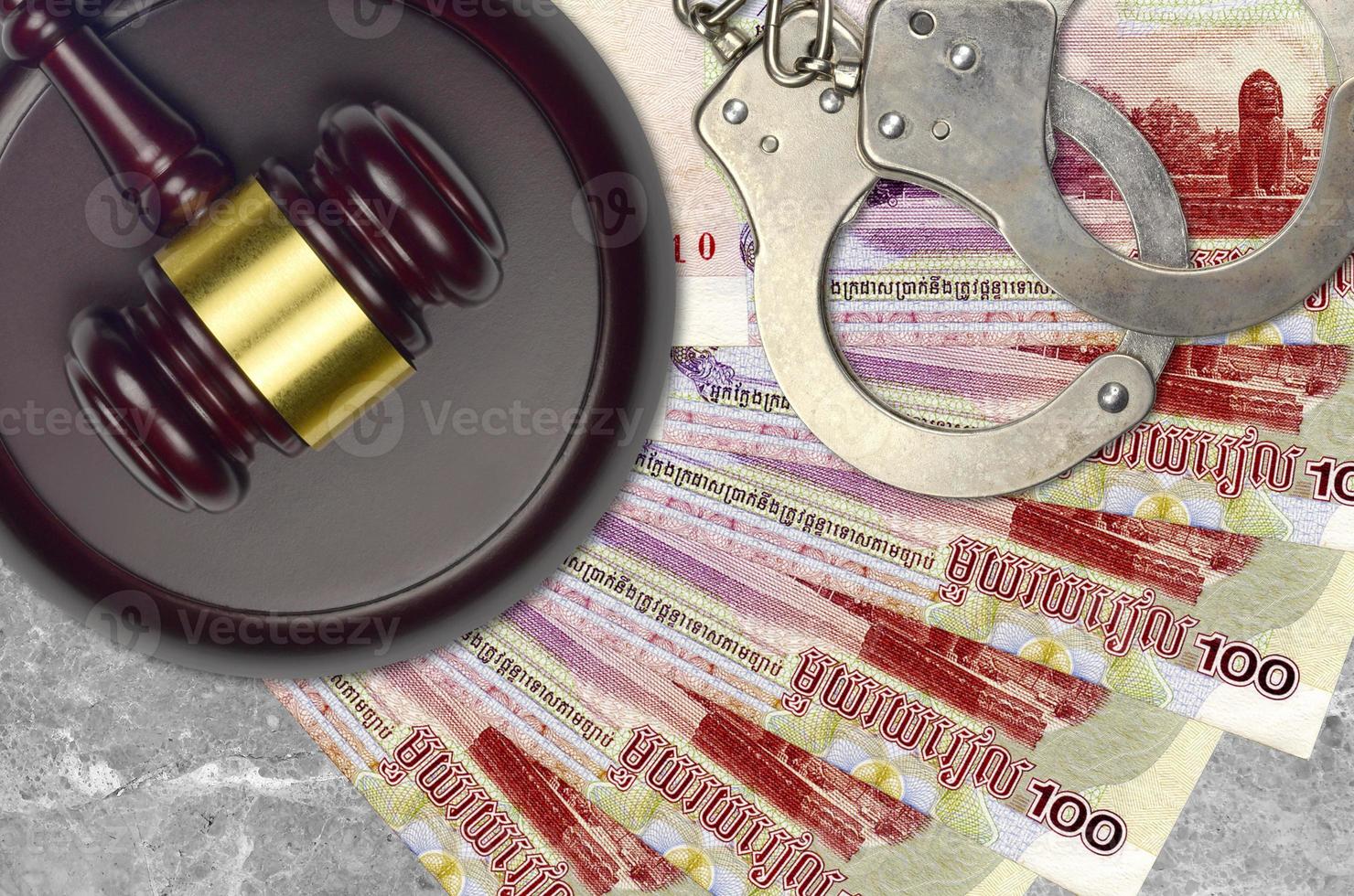 100 Cambodian riels bills and judge hammer with police handcuffs on court desk. Concept of judicial trial or bribery. Tax avoidance photo