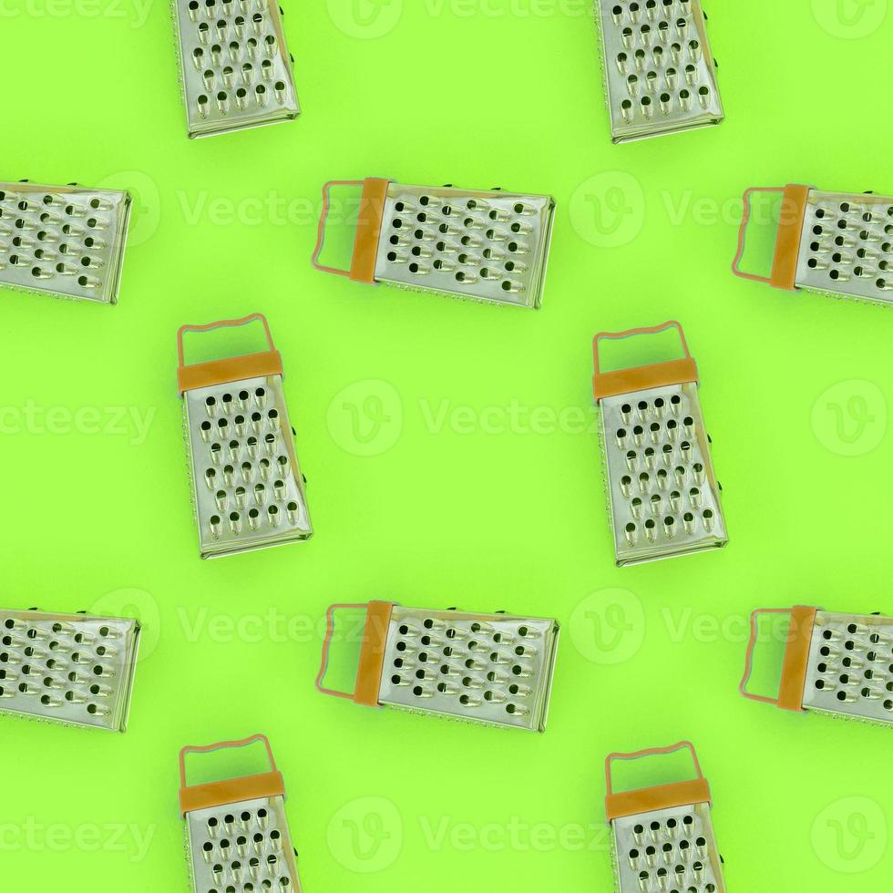 Small stainless steel graters lies on a pastel colored paper. Kitchen accessories. Tools for cooking. Flat lay top view photo