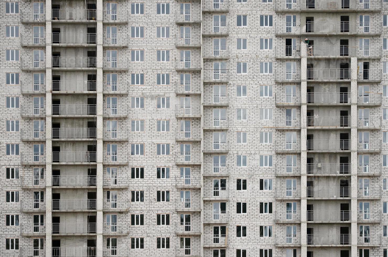Textured pattern of a russian whitestone residential house building wall with many windows and balcony under construction photo