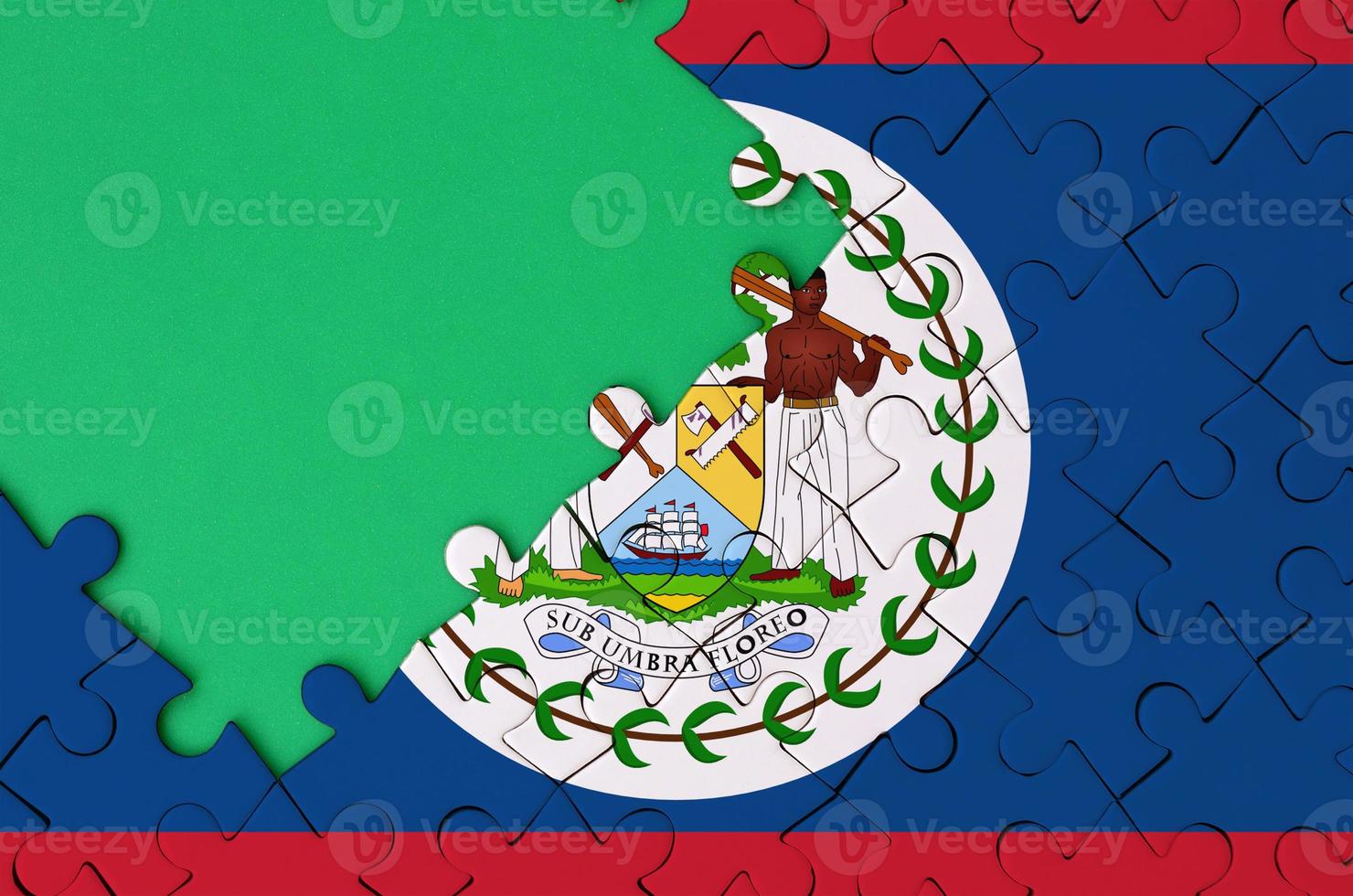 Belize flag  is depicted on a completed jigsaw puzzle with free green copy space on the left side photo