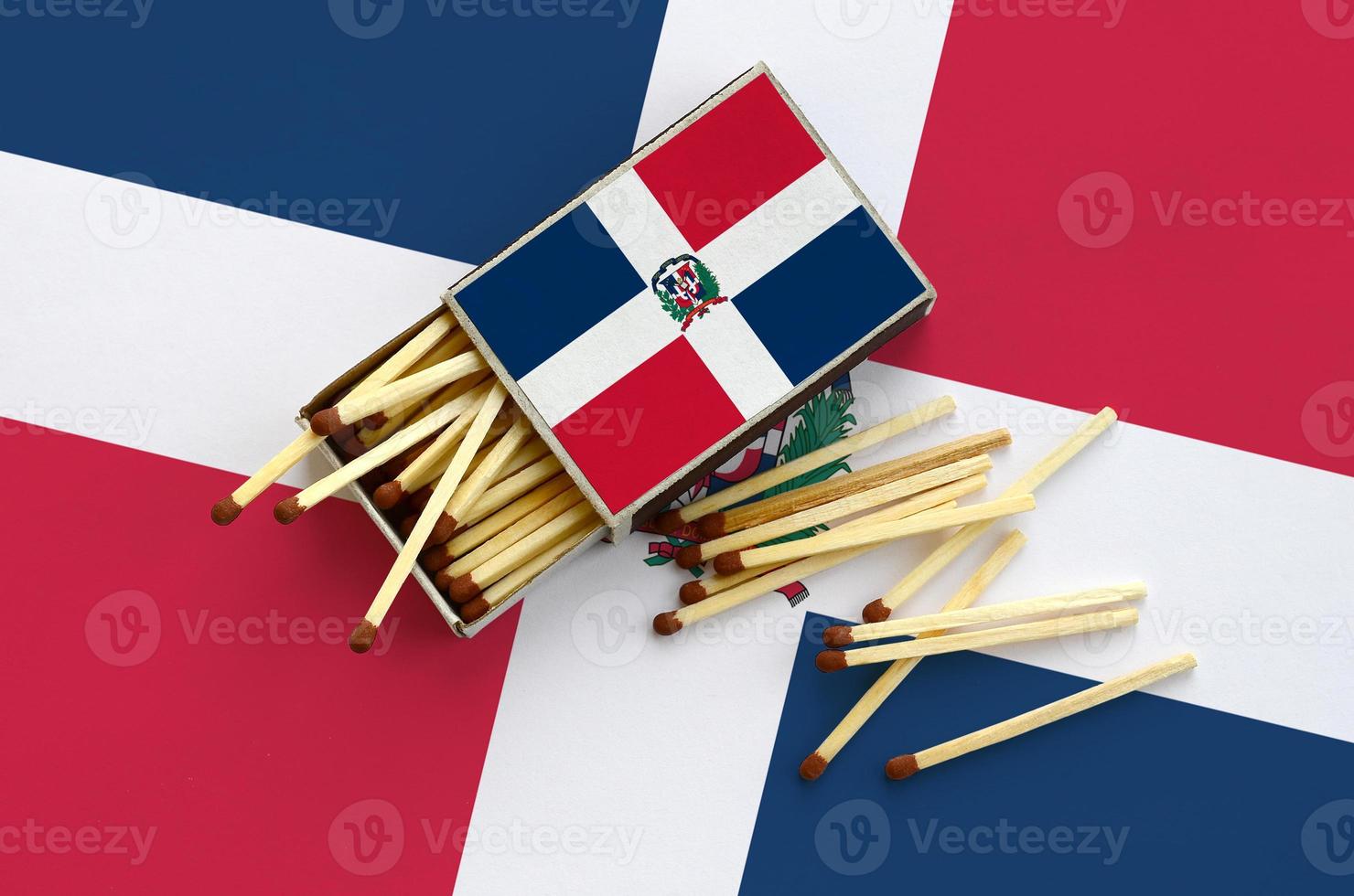 Dominican Republic flag  is shown on an open matchbox, from which several matches fall and lies on a large flag photo