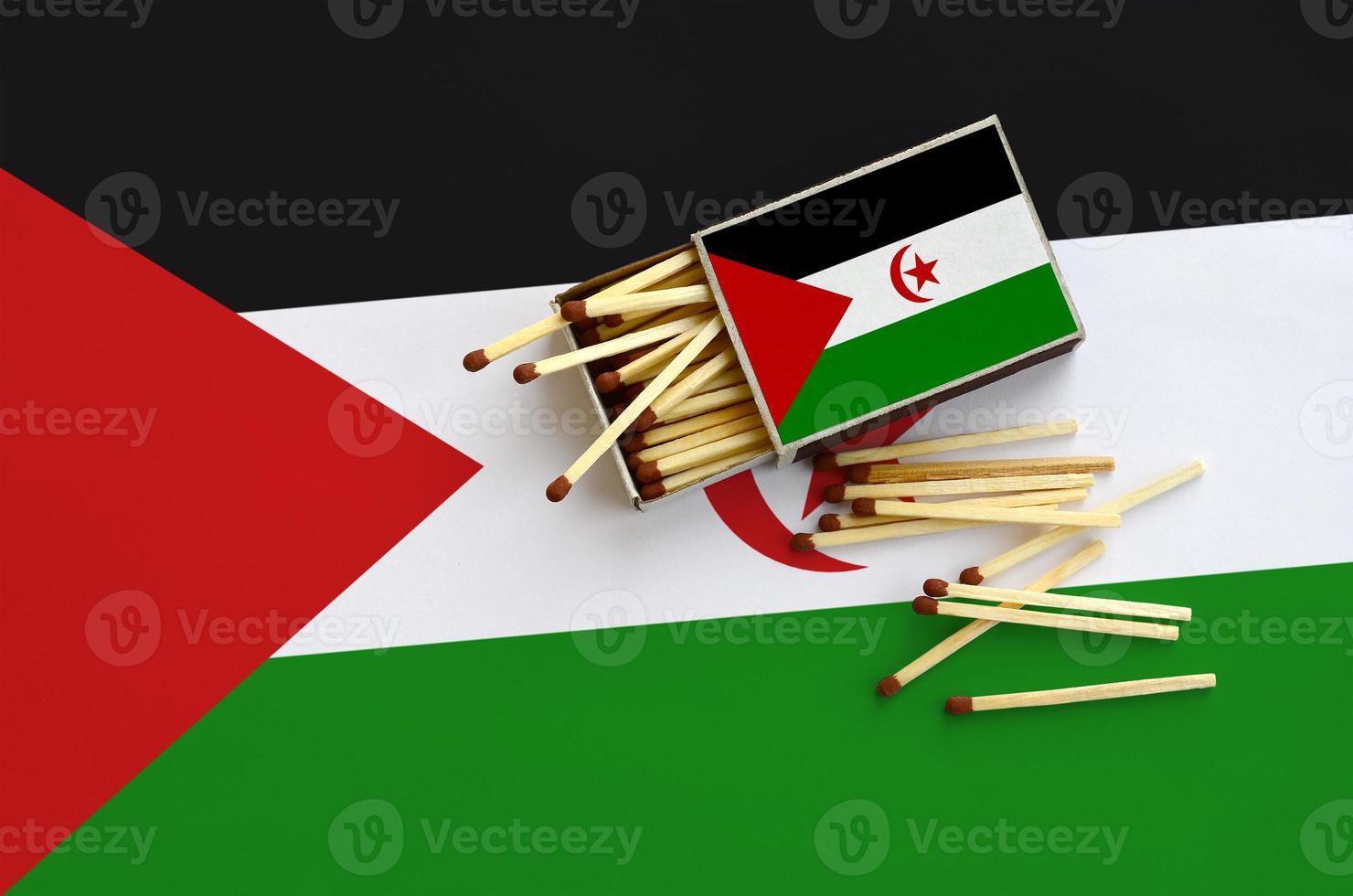 Western Sahara flag  is shown on an open matchbox, from which several matches fall and lies on a large flag photo