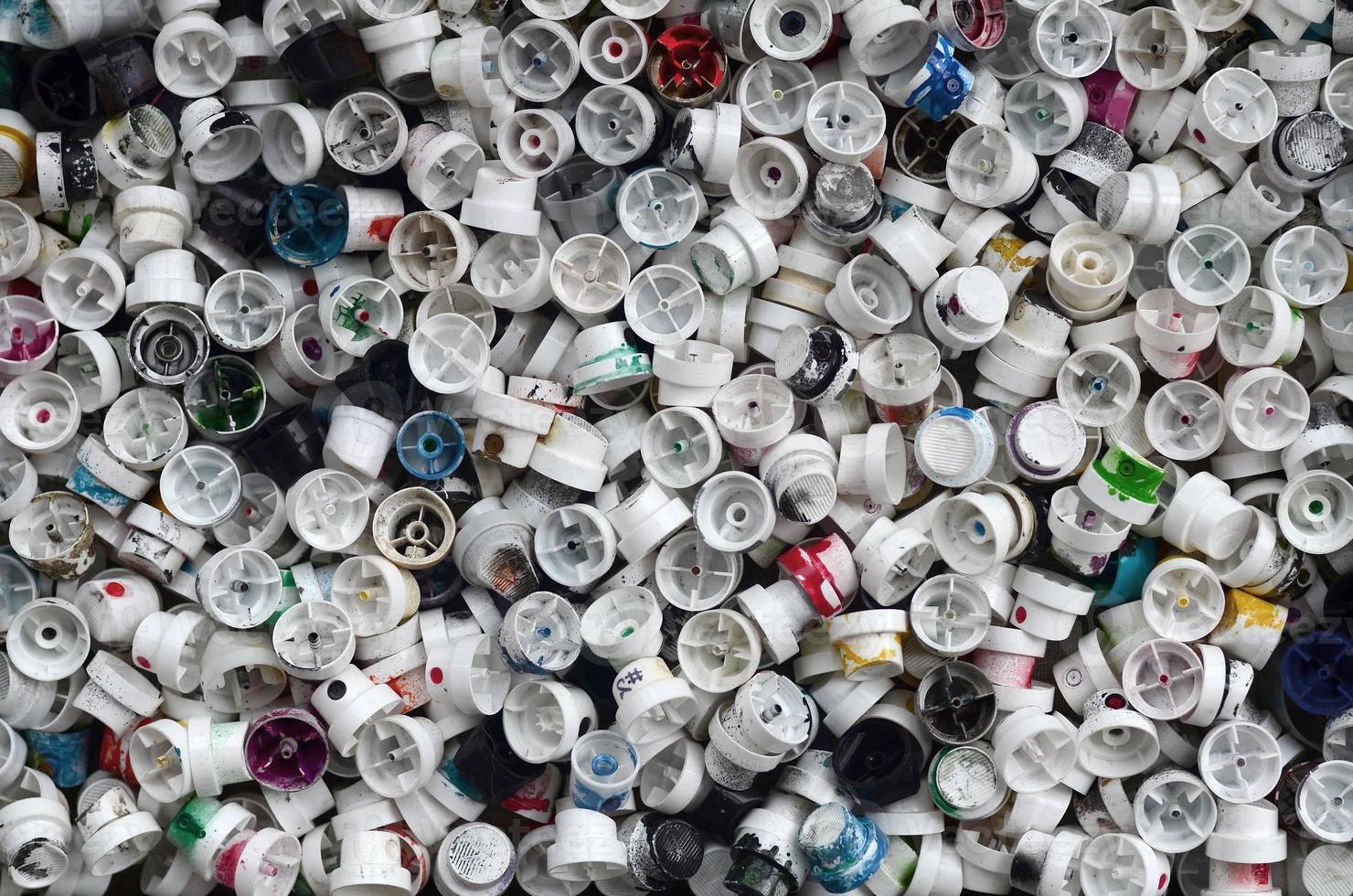 A pattern of many used and soiled nozzles from spray cans with aerosol paint. Background texture of the street art of drawing graffiti on the walls photo
