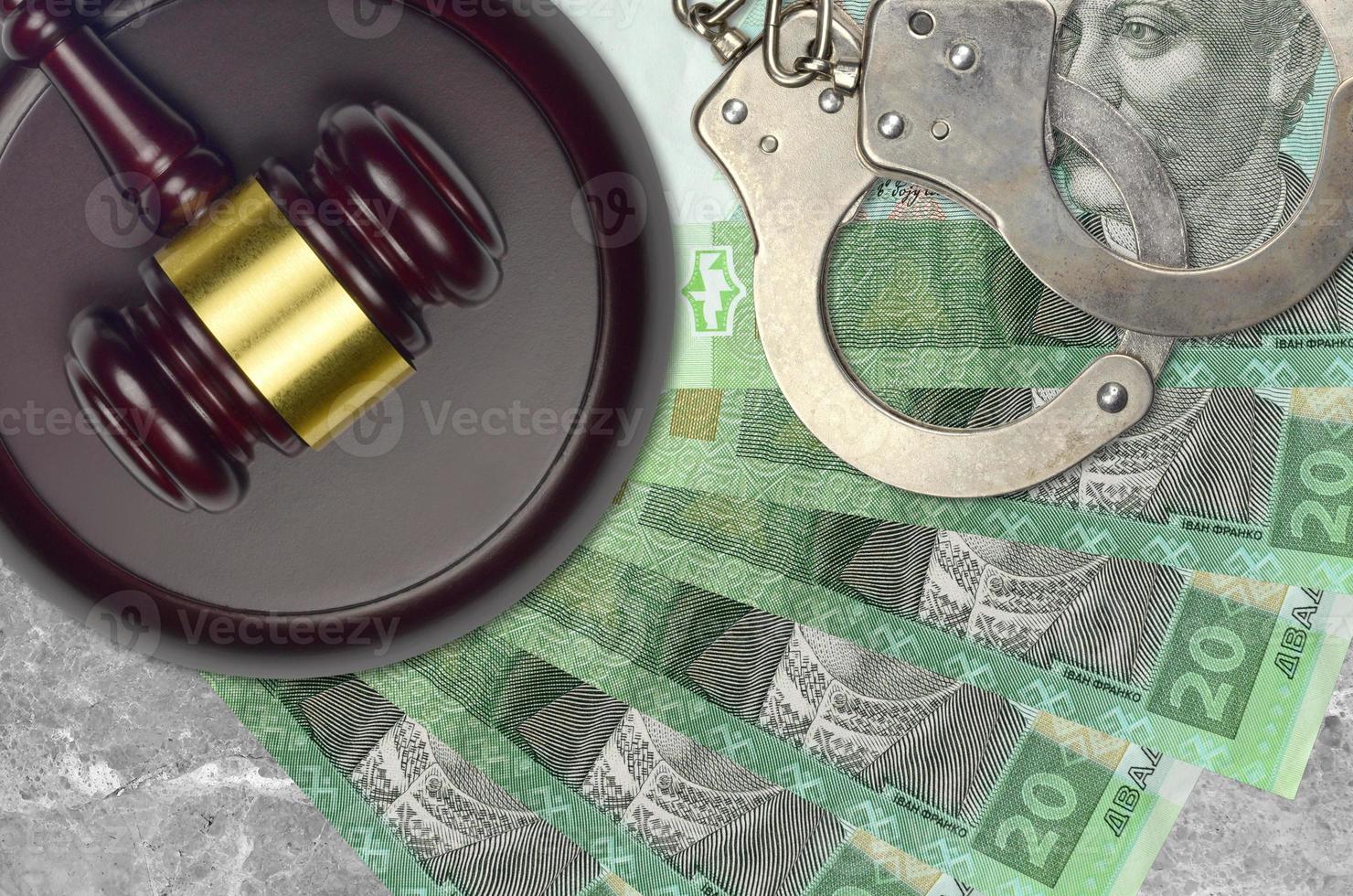 20 Ukrainian hryvnias bills and judge hammer with police handcuffs on court desk. Concept of judicial trial or bribery. Tax avoidance photo